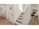 Bright hallway featuring hardwood floors, staircase, and view into the living room with fireplace at 3040 Westgate Park Dr, Loganville, GA 30052