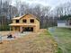 New construction home showcasing the initial framing stage with a large two-car garage nestled in a wooded lot at 305 Melanie Ct, Bowdon, GA 30108