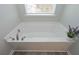 Bright white bathtub with chrome fixtures sits under window with wood-look vinyl flooring at 2960 Fareed St, Douglasville, GA 30135