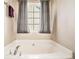 A relaxing, white bathtub with chrome fixtures and natural light from a window at 744 Mesa Rd, Mcdonough, GA 30253