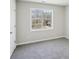 A bedroom featuring light gray walls, neutral carpet, a window with natural light, and a white door at 155 Hitchcock Dr, Villa Rica, GA 30180