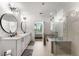 Bright bathroom featuring double vanity, large mirrors, glass shower, and a peek into an adjacent bedroom at 1080 Peachtree Ne St # 1909, Atlanta, GA 30309