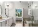 Stylish bathroom with double sinks, a large mirror, a glass-enclosed shower, and a view into the bedroom at 1080 Peachtree Ne St # 1909, Atlanta, GA 30309