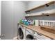 This laundry room features wood shelving and countertop above modern washer and dryer units at 1222 Poston Se Pl, Smyrna, GA 30080
