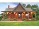 Inviting home with a covered porch, warm lighting, shingle siding, and lush green lawn at 1694 Mount Bethel Rd, Mcdonough, GA 30252