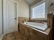 Elegant main bathroom with a large soaking tub with tile surround and bright window at 401 Carrie Kathleen Ter, Carrollton, GA 30116