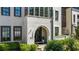 Close up of the home's arched entryway, white brick, manicured landscaping, and dark trim at 6616 Aria Village Dr, Atlanta, GA 30328