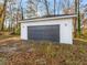 A modern garage with a dark gray door complements the white siding, set against a backdrop of trees and autumn leaves at 741 Se Knox Se Dr, Atlanta, GA 30315