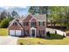 Two-story brick home with a two-car garage, dark shutters, and a landscaped lawn at 949 Tumlin Trce, Lawrenceville, GA 30045