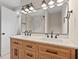 Modern bathroom featuring a double vanity with decorative mirror and sconces with a tiled shower in the background at 19 Grove Park Nw Pl, Atlanta, GA 30318
