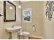 A quaint powder room featuring a pedestal sink, toilet, decorative mirror, and a wall mounted accent at 5060 Governors Walk Dr, Canton, GA 30115