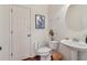 Cozy powder room featuring a pedestal sink, art, and wood floors next to a white painted door at 5890 Vinyard Ln, Cumming, GA 30041