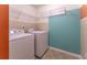 This laundry room features a washer, dryer, wire shelving, tile flooring, and a vibrant teal accent wall at 946 Gardenia Curv, Canton, GA 30114