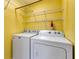 A yellow laundry room features a white washer and dryer with wire shelving above at 2002 Stonewick Ct, Lawrenceville, GA 30043