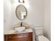 Elegant powder room features a marble vanity, vessel sink, and oval mirror with a wooden cabinet at 2002 Stonewick Ct, Lawrenceville, GA 30043