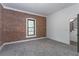 Bedroom features an exposed brick wall, carpet floors, modern window, and a doorway leading to the hallway at 6592 Factory Shoals Sw Rd, Mableton, GA 30126