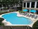 A community pool with lounge chairs and sun umbrellas next to a modern building at 244 13Th Ne St # 302, Atlanta, GA 30309