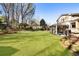Spacious backyard with a large lawn, mature trees, and a covered patio for outdoor enjoyment at 6784 Tilton Ln, Peachtree Corners, GA 30360