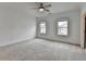 An open bedroom has two windows that bring in natural light, neutral walls, carpet, and crown molding at 1273 Harvest Park Ln, Suwanee, GA 30024