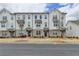 Charming townhouse exterior featuring white brick, symmetrical facade, and black window awnings against a blue sky at 1273 Harvest Park Ln, Suwanee, GA 30024