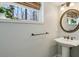 Bathroom featuring a pedestal sink, round mirror, and window with natural light at 2173 Lebaron Ne Dr, Atlanta, GA 30345