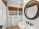 Traditional bathroom with a pedestal sink, framed round mirror, and a window for natural light at 2173 Lebaron Ne Dr, Atlanta, GA 30345