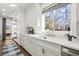 A white kitchen features stone countertops, stainless steel appliances, an island, and natural light from a window at 2758 Chieftain Run, Duluth, GA 30097