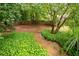 Backyard with lush greenery, brick path, and wooded fence at 1976 Hedge Brooke Nw Trl, Acworth, GA 30101