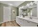 A bathroom features a double sink vanity, wood-look flooring, and an expansive mirror reflecting a walk-in shower at 3031 Clove Tree Ln, Woodstock, GA 30189