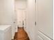 Hallway with wood flooring, multiple doors, and access to a half bathroom with a freezer at 7808 Rutgers Cir, Fairburn, GA 30213