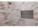 Close-up of marble style tiled shower featuring bronze shower head and tiled niche at 973 Parsons Sw St, Atlanta, GA 30314