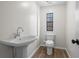 Bathroom featuring a pedestal sink, toilet, and window for natural light at 1833 Lost Mountain Rd, Powder Springs, GA 30127