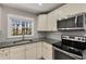 Modern kitchen with stainless steel appliances, granite counters, white cabinetry, and a view of the lush backyard at 2462 Macon Sw Dr, Atlanta, GA 30315