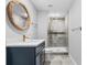 Modern bathroom featuring a navy blue vanity, a round mirror, gold fixtures, and a tiled shower at 2672 Langland Ne Ct, Atlanta, GA 30345