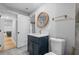 Modern bathroom featuring a navy blue vanity, a round mirror, gold fixtures, and a white toilet at 2672 Langland Ne Ct, Atlanta, GA 30345