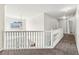 Upstairs hallway with white railings, neutral walls and carpet, and a decorative light fixture at 4001 Oak Field Dr, Loganville, GA 30052