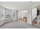 Open-concept living room boasts plush gray carpeting, large windows, and seamless flow to the staircase at 4001 Oak Field Dr, Loganville, GA 30052