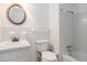 Bathroom with a toilet, shower and bath with white tile, a round mirror above the sink at 803 Denise Sw Ct, Stone Mountain, GA 30087