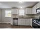 Well-lit kitchen featuring granite counters, white cabinetry, stainless appliances, and wood-look flooring at 5415 Tracey Dr, Stone Mountain, GA 30088