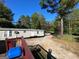 Exterior view showcasing a mobile home with a surrounding yard and wooded landscape at 615 Woodruff Rd, Carrollton, GA 30116