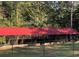 Large outdoor pavilion with a red metal roof, partially enclosed by fencing at 615 Woodruff Rd, Carrollton, GA 30116