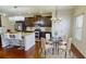 Well-lit kitchen featuring a decorative island, dark wood cabinetry, and a dining area with seating for four at 2409 Brynfield Cv, Suwanee, GA 30024