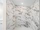 Modern shower featuring elegant marble-patterned tile and pebble flooring at 75 Woodfield Rd, Covington, GA 30014