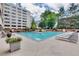 Community pool area with lounge chairs, a grill, greenery, and a bright blue pool at 878 Peachtree Ne St # 535, Atlanta, GA 30309