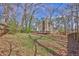 Large backyard featuring a wooden fence, mature trees, and a deck attached to the two-story home at 585 Lake Dr, Snellville, GA 30039