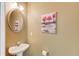 Powder room with pedestal sink and round mirror, decorated with a nature-themed painting at 1554 Park Grove Dr, Lawrenceville, GA 30046