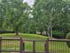 View from a back deck overlooking a lush lawn with mature trees and a black fence at 2467 Sky Valley Dr, Dacula, GA 30019
