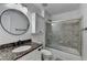 Bathroom featuring granite countertop, glass enclosed shower over tub and round mirror at 2467 Sky Valley Dr, Dacula, GA 30019