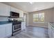 Bright kitchen features white cabinets, stainless steel appliances, and wood flooring near an eating area with natural light at 3021 Hampton Club Way, Lithonia, GA 30038