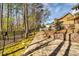 Landscaped backyard featuring a stone patio, terraced garden beds, and a classic wrought iron fence at 6921 Springbank Way, Stone Mountain, GA 30087